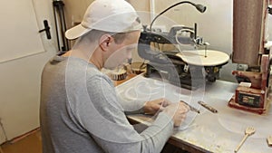 A male carpenter grinds the workpiece with sandpaper in a carpentry workshop