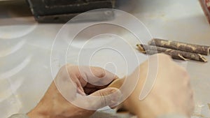 A male carpenter grinds the workpiece with sandpaper in a carpentry workshop