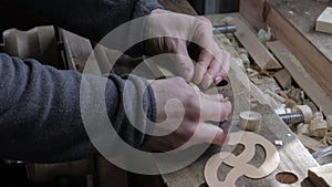 Male carpenter measuring wooden plank for the pine shelf with curved and straight ruler and marking it with a pencil