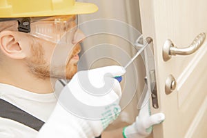 Male carpenter wood door installation working tightens lock