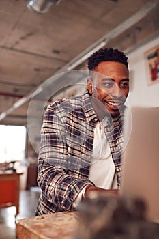 Male Carpenter In Workshop Doing Accounts On Laptop