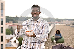 Male in casual shirt, with fork in hand and vegetable salad in bowl.