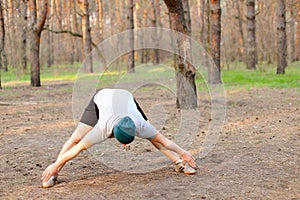 Male caucaian person doing stretch marks in morning park.