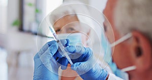 Male caucasian doctor holding syringe while senior caucasian woman wearing face mask sitting with sl