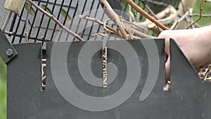 Male Caucasian hand setting fire to bbq grill with match. Close-up of unrecognizable man lighting up barbecue outdoors