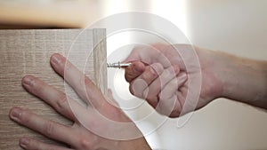 Male caucasian hands manually twist skrew with metal hex key, close-up.