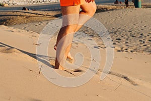 Male caucasian legs on sand dune beach. man gets down from a sand dune. Suntan, resting, relaxing. Selective focus