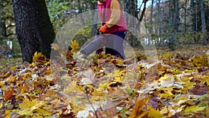 Male caucasian worker using leaf blower to blow autumn leaves from grass lawn