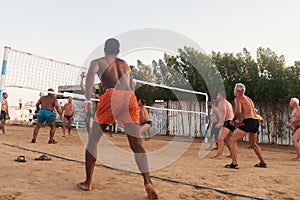 male Caucasians, Arabs, Africans playing volleyball on the beach