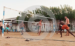 male Caucasians, Arabs, Africans playing volleyball on the beach