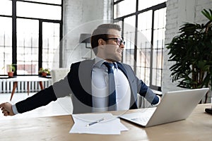 Male CEO stretch at desk in office finishing work