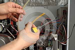 A male checks a gas boiler for home heating. Maintenance and repair of gas heating