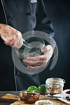 Male chef blending herbs in a mortar and pestle photo