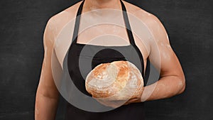 Male chef with bread in his hand on a black background. Cooking concept