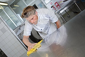 Male chef cleaning stainless steel kitchen work surface