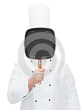 Male chef cook covering face with grill pan