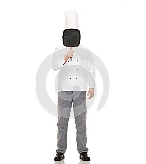 Male chef cook covering face with grill pan