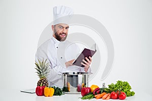 Male chef cook holding recipe book and preparing food