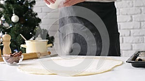 male chef cooking cinnamon rolls , pouring sugar on the dough