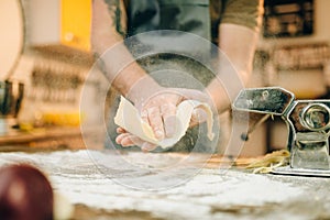 Male chef cooking dough and prepares pasta machine