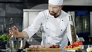 Male chef cooking meat at professional kitchen. Portrait of chef cooking steak.