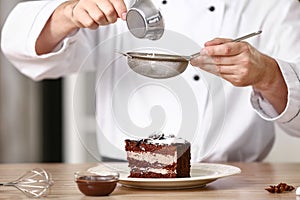 Male chef decorating tasty dessert in kitchen, closeup