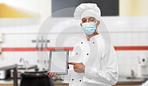 Male chef in face mask with tablet pc at kitchen