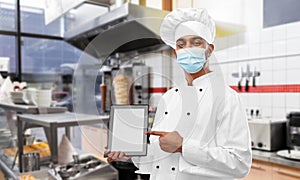 Male chef in face mask with tablet pc at kitchen