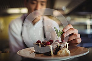 Male chef garnishing dessert plate