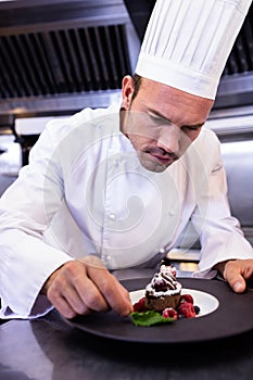 Male chef garnishing dessert plate photo