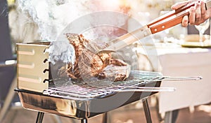 Male chef grill t-bone steak at barbecue dinner outdoor - Man cooking meat for a family bbq meal outside in backyard garden -