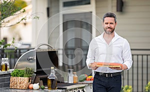 Male chef grilling and barbequing salmon fillet in garden. Barbecue outdoor garden party. Handsome man preparing