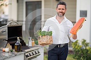 Male chef grilling and barbequing salmon fillet in garden. Barbecue outdoor garden party. Handsome man preparing