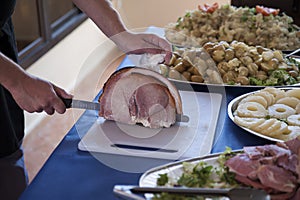 Male chef hand with knife slicing a crispy roasted pork joint