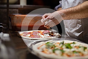 Male chef hands making pizza in the pizzeria kitchen