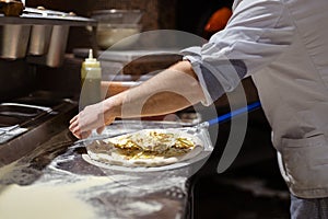 Male chef hands making pizza in the pizzeria kitchen