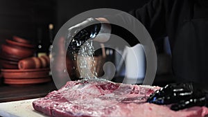 Male chef hands sprinkling salt meat piece cooking delicious food restaurant kitchen closeup slowmo