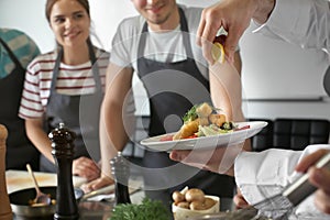 Male chef holding plate with prepared dish during cooking classes photo