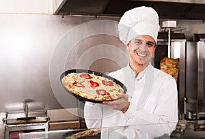 Male chef with Italian pizza at bistro