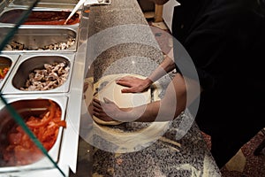 Male chef kneading and rotating dough basis for pizza