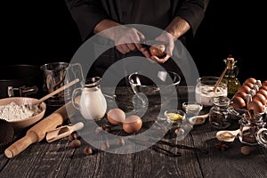 Male chef prepares fragrant cake with lots of spices. Dark key