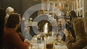 Male chef prepares meal in flambe style in front of people