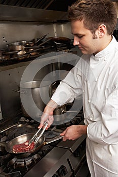 Masculino cocinero preparación comida sobre el cocina en un restaurante 
