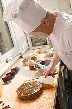 Male chef spreading apricot marmalade on cake