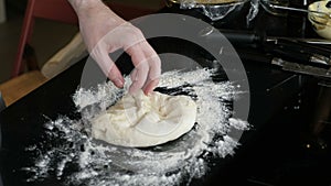 Male chef sprinkles flour on the table and makes dough