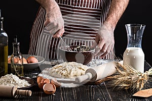 Male chef whipping eggs in the bakery on wooden table. Ingredients for cooking flour products or dough