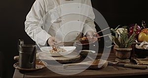 Male chef in white uniform prepares spaghetti with vegetables on the dish