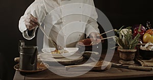 Male chef in white uniform prepares spaghetti with vegetables on the dish