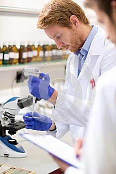 Male chemical scientist place sample of liquid on microscope sli