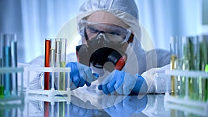 Male chemist checking test tubes with biohazard substance, toxicology testing photo